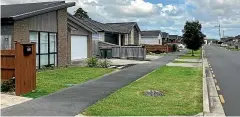  ?? KATE NEWTON/ STUFF ?? An open stormwater system in this Takanini developmen­t includes shallow grass swales instead of pipes. The metal grate covers a recharge pit designed to hold water.