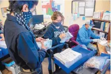  ?? EDDIE MOORE/JOURNAL ?? From left, Larry Vigil, Brenda Lee Gallegos and David Martinez scan absentee ballots to verify them against the Rio Arriba County Clerk’s list.