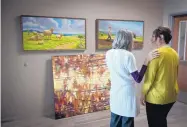  ??  ?? Elena Oates, left, and Rose Pando, right, both Catholic Charities employees, chat about paintings by Miguel Grave de Peralta and B.C. Nowlin that will adorn the walls of Casa Corazon, the new Catholic Charities center.