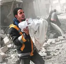  ??  ?? Above: A man carries an infant rescued from the rubble of buildings following the regime’s bombing of Hammuriyeh, Eastern Ghouta, on Monday.