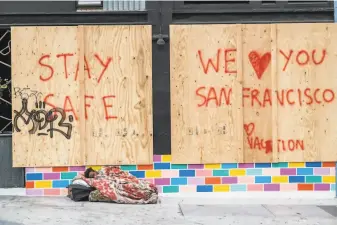  ?? Nick Otto / Special to The Chronicle ?? A homeless man sleeps near a boardedup store in San Francisco in March. Despite fears of high numbers of virus infections, the rate among the homeless is similar to that of the housed.