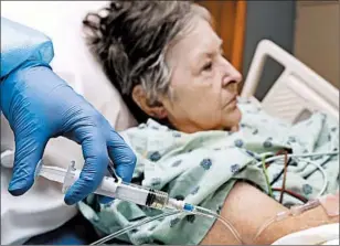  ?? TONY DEJAK/AP ?? A patient in Toledo, Ohio, receives an IV push of antibiotic­s. Amid a severe shortage of crucial sterile fluids, hospitals have turned to substitue supplies and alternate procedures.