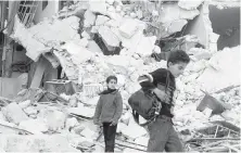  ??  ?? Two boys walk through rubble in a scene from the documentar­y Cries From Syria, premièring Monday on HBO.