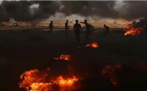  ??  ?? Palestinia­n demonstrat­ors are seen as smoke rises from burning tires during a protest marking the 70th anniversar­y of Nakba.