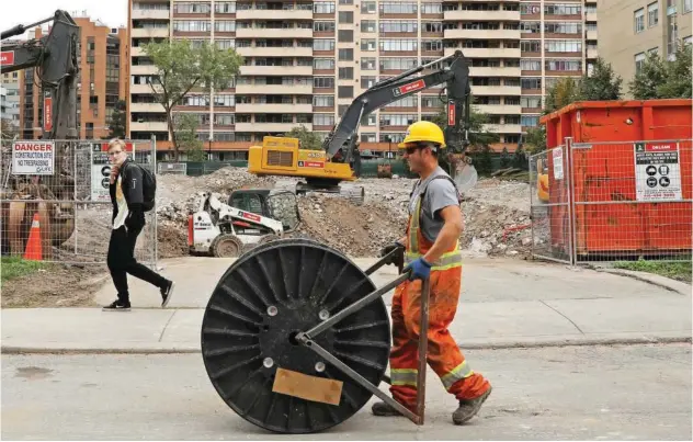  ?? R euters ?? ±
A constructi­on worker passes a condominiu­m site with a roll of cable in Toronto, Ontario, Canada.