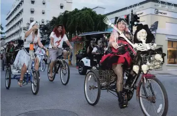  ?? Monroe County Tourist Developmen­t Council ?? Costumed bicycle riders roll down Duval Street in Key West on Oct. 24. Although large-scale events were canceled due to the COVID-19 pandemic, the annual Fantasy Fest celebratio­n continues through Sunday.