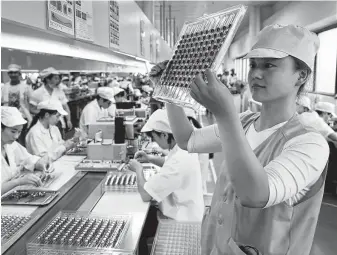  ?? Associated Press ?? A worker inspects micro-motors for handsets at a factory in China. President Trump is expected to sign a law this week that will increase oversight for foreign investment in U.S. technology.