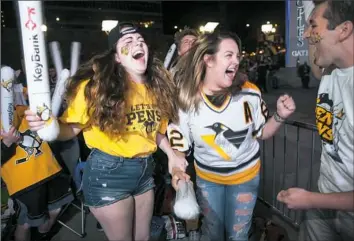  ??  ?? From left, Kathleen Rhoa, 21, of Uptown; Kassy Spirik, 20, of Uptown; and Austin Gagliardi, 21, of Mount Washington, celebrate outside PPG Paints Arena after the Penguins scored in their game against the Ottawa Senators.