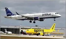  ?? JOE CAVARETTA — SUN SENTINEL/TNS ?? A JetBlue airliner lands past a Spirit Airlines jet on a taxiway at Fort Lauderdale Hollywood Internatio­nal Airport in Florida on April 25.
