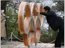  ?? (AP/Kim Kyung-Hoon) ?? A man poses with a display of the Olympic symbol Wednesday on Mount Takao in Hachioji, located west of Tokyo. Wednesday marked 100 days before the scheduled start of the Tokyo Olympics.