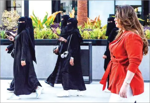  ?? FAYEZ NURELDINE/AFP ?? Saudi human resources profession­al Mashael al-Jaloud, 33, walks in western clothes past women wearing women, at a commercial area in the Saudi capital Riyadh on September 3. an Islamic dress-code for