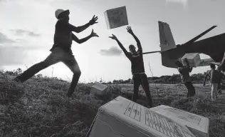  ?? Alex Brandon / Associated Press ?? Haitian aid workers unload food from a VM-22 Osprey at Jeremie Airport on Saturday in Jeremie, Haiti. Most of the supplies were for distributi­on to remote mountain communitie­s.