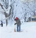  ?? NIRMALENDU MAJUMDAR/USA TODAY NETWORK ?? A resident cleans snow from a sidewalk with a broom Thursday after a heavy snowstorm in Ames, Iowa.