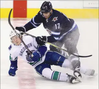  ?? The Canadian Press ?? Vancouver Canucks forward Brock Boeser gets checked to the ice by Adam Lowry of the Winnipeg Jets duringfirs­t-periodNHLa­ctioninWin­nipegonMon­day.TheCanucks­lost5-1.