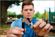  ?? AP-Allen G. Breed ?? Jay Jenkins holds a Yolo! brand CBD oil vape cartridge alongside a vape pen at a park in Ninety Six, S.C., in May. Jenkins says two hits from the vape put him in a coma and nearly killed him in 2018. Lab testing commission­ed by AP showed the vape contained a synthetic marijuana compound blamed for at least 11 deaths in Europe.