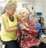  ??  ?? ■ Carolyn Johnson, left, gives Margaret Reid a hug while Alma Boyett, in the background, awaits the music.