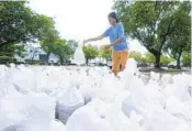  ?? WILFREDO LEE AP ?? City worker Shalimar Mohammed stacks sandbags at a distributi­on area Friday in Miami.