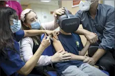  ?? AP photo ?? Israeli child Rafael Peled, 8, looks through a VR virtual reality goggles as he receives a Pfizer COVID-19 vaccine from medical staff at the Sheba Tel Hashomer Hospital in Ramat Gan, Israel on Nov. 22.