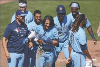  ?? AP PHOTO/MIKE CARLSON ?? Members of the Toronto Blue Jays celebrate with Bo Bichette, center, after his game-winning home run against the New York Yankees during the ninth inning of a baseball game Wednesday in Dunedin, Fla. The Blue Jays won 5-4.