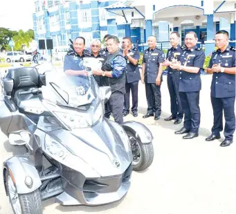  ??  ?? Omar presenting a crash helmet to Deputy Police Commission­er Datuk Zaini Jass (le ) to mark the launch of a motorcycle convoy in conjunctio­n with the Sabah police crime prevention campaign yesterday.