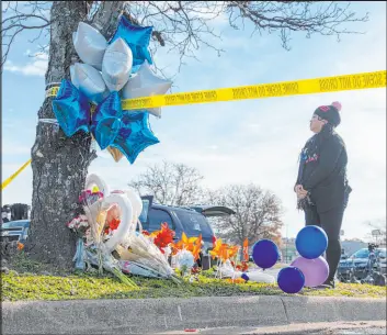  ?? Billy Schuerman The Associated Press ?? Mary Chatkovsky places balloons and flowers Thursday on a memorial outside of the Chesapeake, Va., Walmart, where a supervisor killed six fellow employees Tuesday.