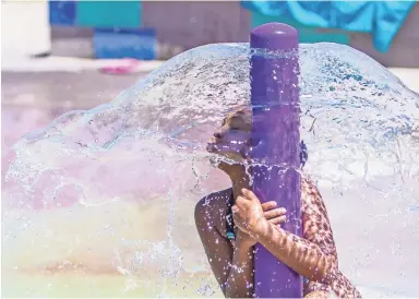  ?? JOHANNA HUCKEBA/THE REPUBLIC ?? Layla Kelly, 8, finds a perfect place to keep her body cool as she plays at the Cloud splash pad at Kiwanis Park in Tempe. The heat’s effects on health will continue to be concerning this week with high temperatur­es in the Valley forecast to be at least 113 degrees today and Wednesday.