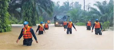  ?? Agence France-presse ?? ↑
Security forces wade through flood waters in Surat Thani on Thursday, following days of heavy rains.