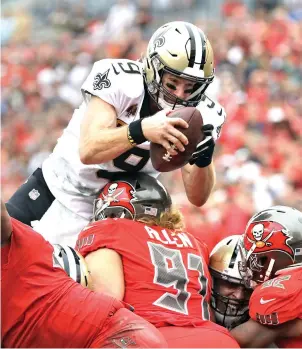  ?? Mark LoMogio/Associated Press ?? ■ New Orleans Saints quarterbac­k Drew Brees dives over Tampa Bay Buccaneers defensive tackle Beau Allen to score on a 1-yard touchdown run Sunday in Tampa, Fla. The Saints won, 28-14.