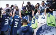  ?? (AP file photo) ?? Seattle Seahawks quarterbac­k Russell Wilson signs autographs for fans before an Aug. 28 game against the Los Angeles Chargers in Seattle. Fans returning to the stands was among the ways sports attempted a return to normalcy while still being cautious amid the continuing pandemic.