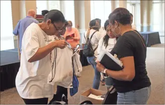  ?? / Spencer Lahr ?? Cheryl Freeman Snipes (left), the president of the Freemantow­n Historical Society, hands out bags during the Freemantow­n families reunion at the Berry College Krannert Center on Saturday.