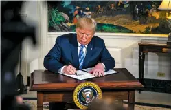  ?? AL DRAGO/BLOOMBERG NEWS ?? President Donald Trump signs a memorandum on Tuesday that the U.S. will withdraw from the accord to curb Iran’s nuclear program.