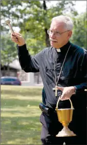  ?? Special to the Democrat-Gazette/KAREN SCHWARTZ ?? Waving an aspergillu­m, Bishop Anthony Taylor blesses the grounds of St. Scholastic­a during the ground-breaking celebratio­n.