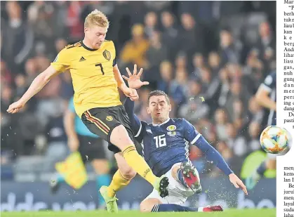  ?? — Gambar AFP ?? AKSI HEBAT: Pemain tengah Scotland, Kenny McLean gagal menghalang De Bruyne (kiri) daripada melepaskan rembatan ketika beraksi di Hampden Park, Glasgow kelmarin.