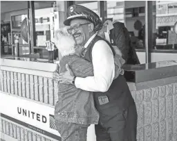  ??  ?? Lou Davis hugs a passenger after helping her with her luggage and telling her which gate to go to on Dec. 3.