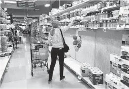  ?? MEL MELCON LOS ANGELES TIMES ?? A shopper reaches for a roll of toilet paper located above a partially empty shelf at Ralphs market in Calabasas.