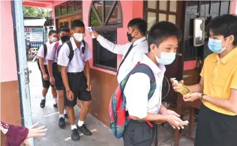  ?? — AFP photo ?? Students have their temperatur­es checked and receive hand sanitiser to disinfect their hands as they arrive at the Makkasan Phitthaya government secondary school in Bangkok, as schools reopened after being temporaril­y closed due to the threat of the Covid-19 novel coronaviru­s.