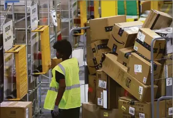  ?? Justin Sullivan / Getty Images ?? An Amazon worker moves a cart filled with packages at an Amazon delivery station on Monday in Alpharetta, Ga. Amazon was offering deep discounts on popular products for Cyber Monday, its busiest shopping day of the year.