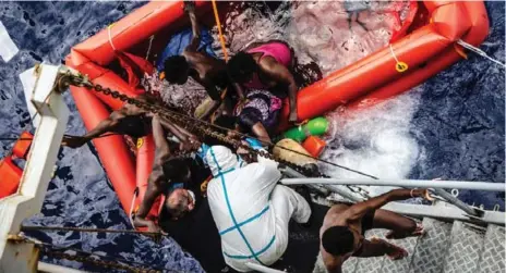  ?? MARINA MILITARE/RAFFAELE MARTINO/THE ASSOCIATED PRESS ?? Crew members of Italian navy ship Vega help rescued migrants clamber aboard after the boat they were on sank off the Libyan coast on Friday.