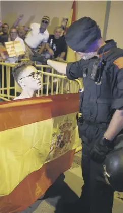  ??  ?? 0 A Catalan police officer orders a protester to move back as a crowd waves Spanish flags in front of a Guardia Civil barracks