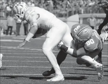  ?? Jay LaPrete/Associated Press ?? Ohio State defensive lineman Tommy Schutt, right, brings down Maryland quarterbac­k Perry Hills during the second quarter on Oct. 10 in Columbus. Hills was a problem for the Buckeyes’ defense, as he ran for 170 yards and two touchdowns.