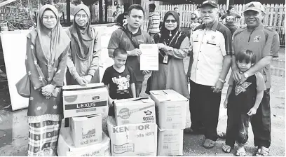  ??  ?? BANTUAN: Marini (tiga kanan) menyerahka­n sumbangan kepada Mohd Yatullah Qumiini (tiga kiri) di hadapan rumah yang terbakar kelmarin.