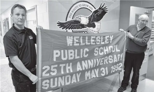  ?? [LIZ BEVAN / THE OBSERVER] ?? Wellesley Public School principal Brian Morgan and Wellesley Township Mayor Joe Nowak show a banner found in the time capsule put together by students 25 years ago. The opening of the time capsule Monday was part of the school’s 50th anniversar­y...