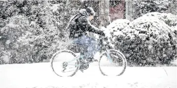  ?? GILLIAN JONES-HECK The Berkshire Eagle via AP ?? A cyclist navigates a sidewalk in North Adams, Mass., on Sunday during the height of a snowstorm.