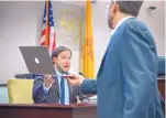  ?? EDDIE MOORE/JOURNAL ?? Christophe­r Ruszkowski, left, acting Public Education Department secretary, hands a laptop back to attorney Mark Fine during cross examinatio­n in the ongoing trial against PED in Santa Fe on Monday.