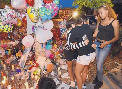  ?? JIM THOMPSON/JOURNAL ?? Destiny Banks, right, comforts her friends Jessica Quintana and Estrella Hurtado at the memorial Thursday night outside the apartment where 10-year-old Victoria Martens was killed early Wednesday.