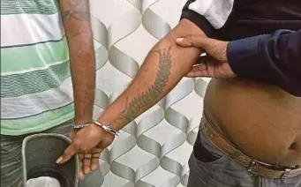  ??  ?? ANGGOTA polis tahan dua individu yang mempunyai tatu.