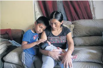  ??  ?? IN THE DARK: Guatemalan migrant Aura Gaspar with two-week old baby Ashley and son Isaac, five, in their home in Immokalee.