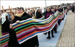  ?? JUAN GONZALEZ / REUTERS ?? Indigenous Mapuche women in Puerto Saavedra, Chile, carry their looms on May 21 while seeking to break a world record by gathering loom weavings that together measure more than one kilometer.