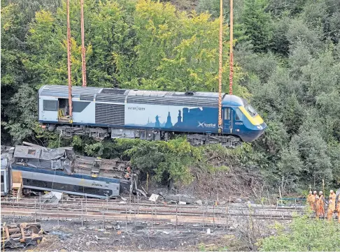  ??  ?? TRAGEDY: A carriage is lifted by crane from the site of the rail crash which claimed the lives of three people at Carmont, south of Stonehaven.