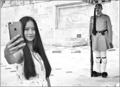  ??  ?? A Chinese tourist takes a photograph of the Tomb of the Unknown Soldier on Syntagma Square in Athens.